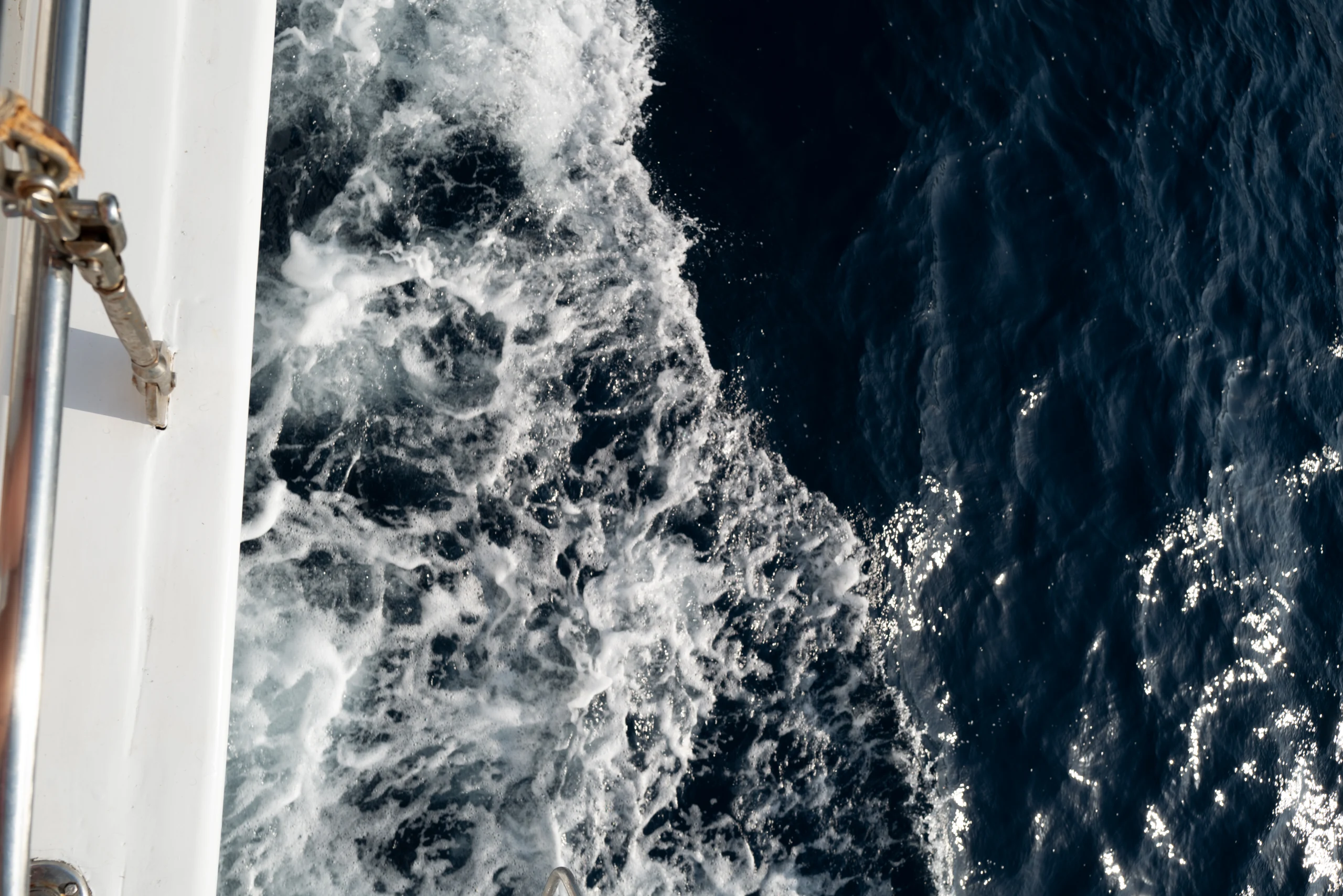 White wake curls through dark blue water alongside the boat.