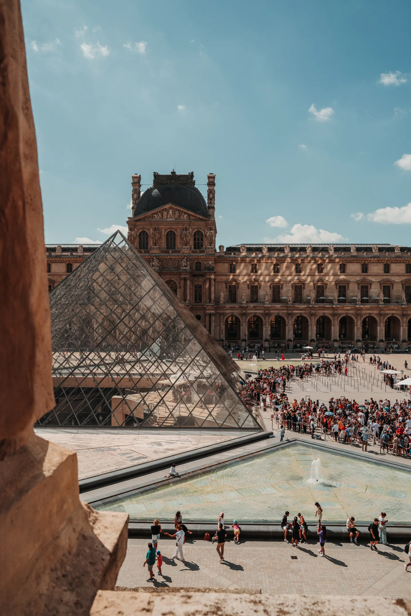 Louvre pyramid seen through a stone opening.