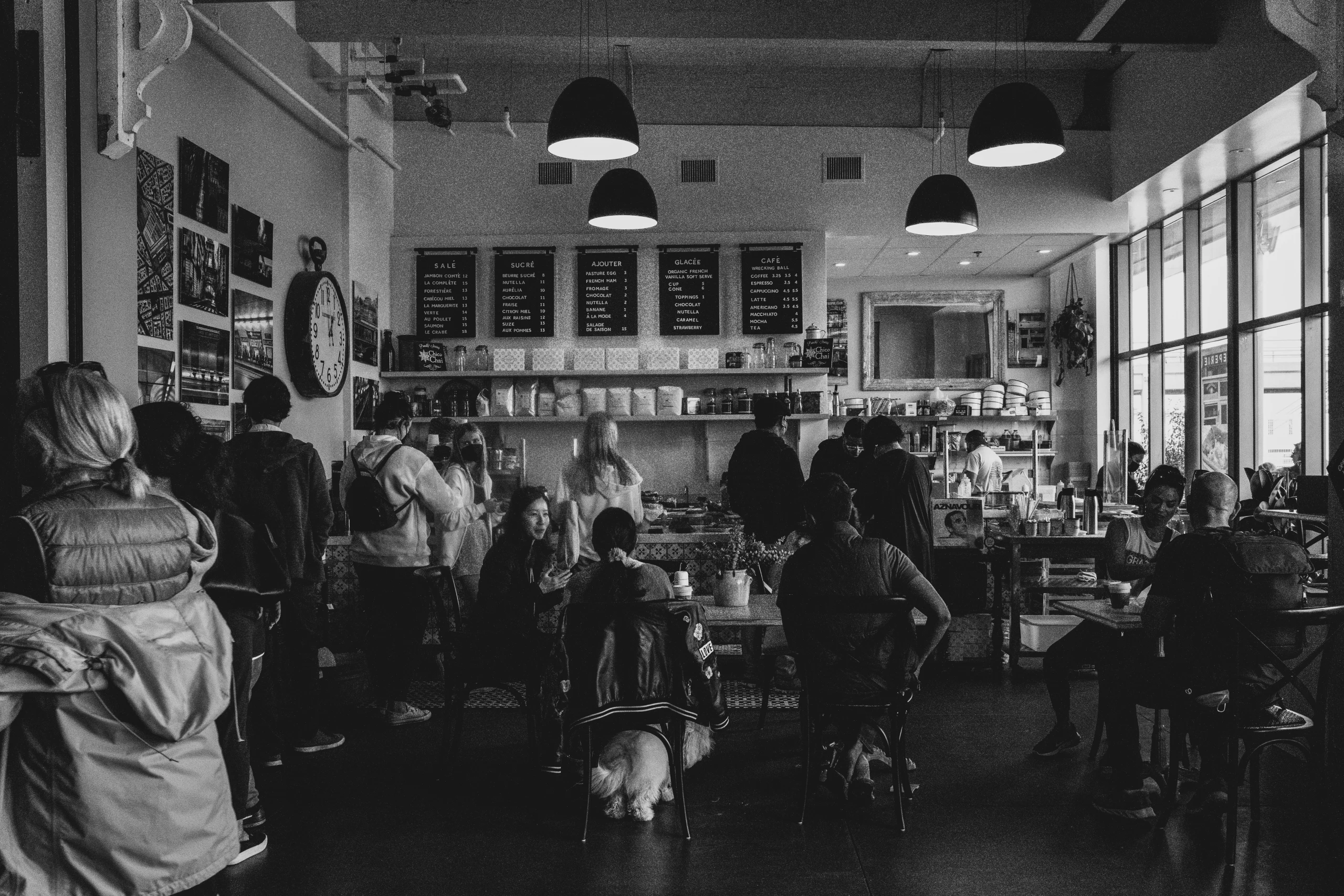 Black-and-white photograph of diners in a bright daytime cafe.