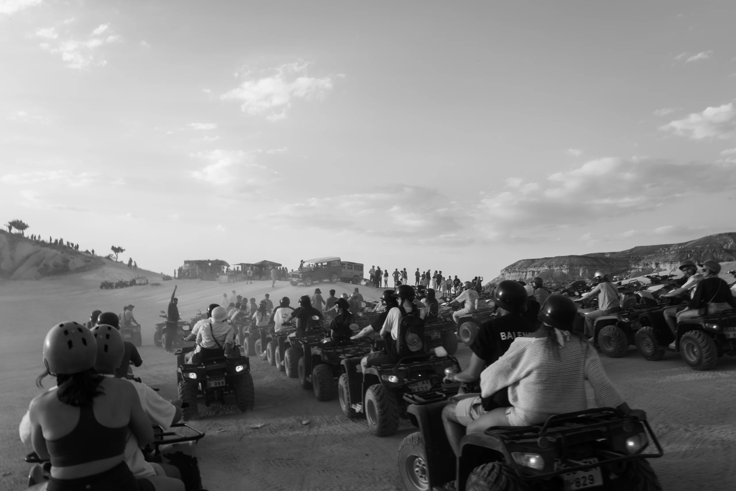 Black-and-white photograph of a crowd of ATV riders gathered on a dusty plain.