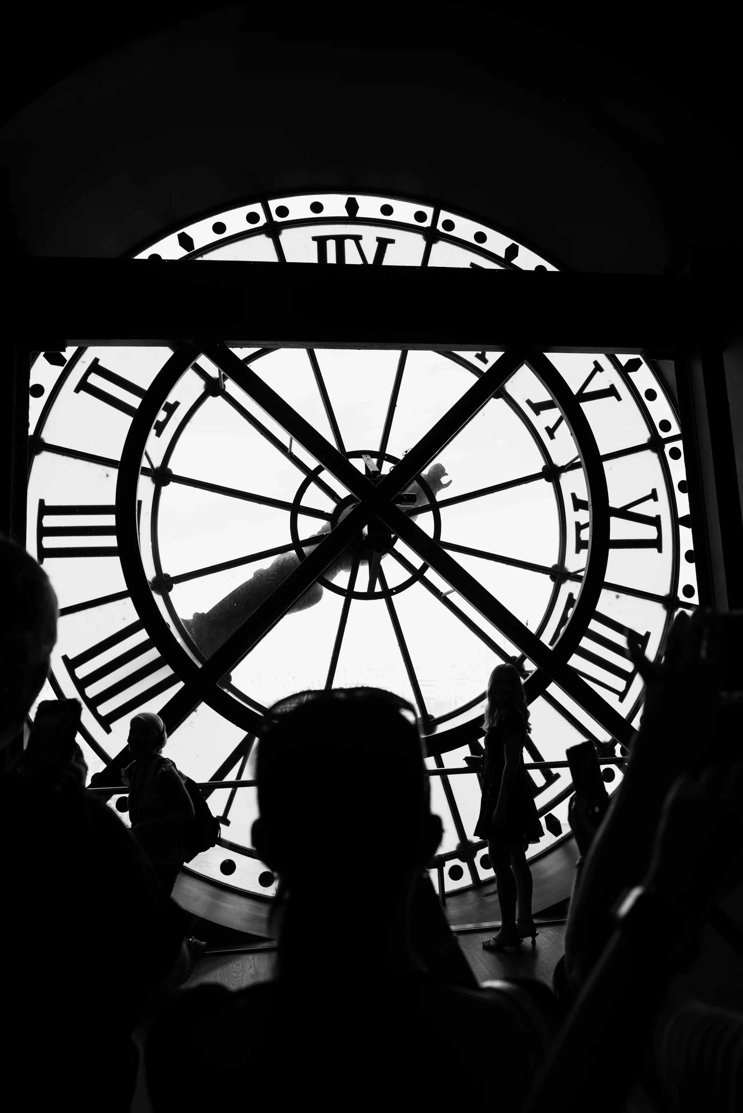 Figure silhouetted inside a monumental clock window.