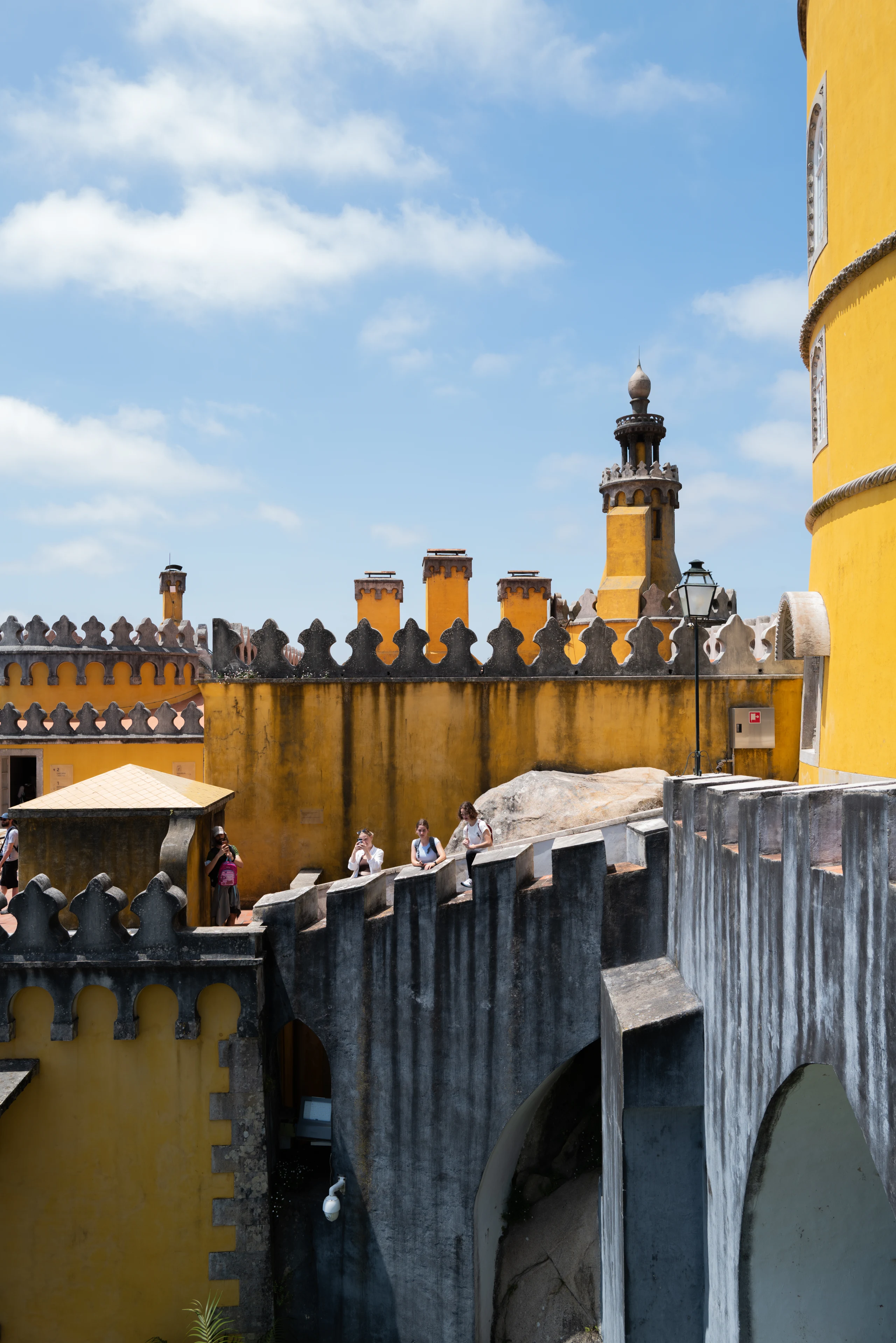 Yellow palace walls and chimneys stand beneath a blue sky.