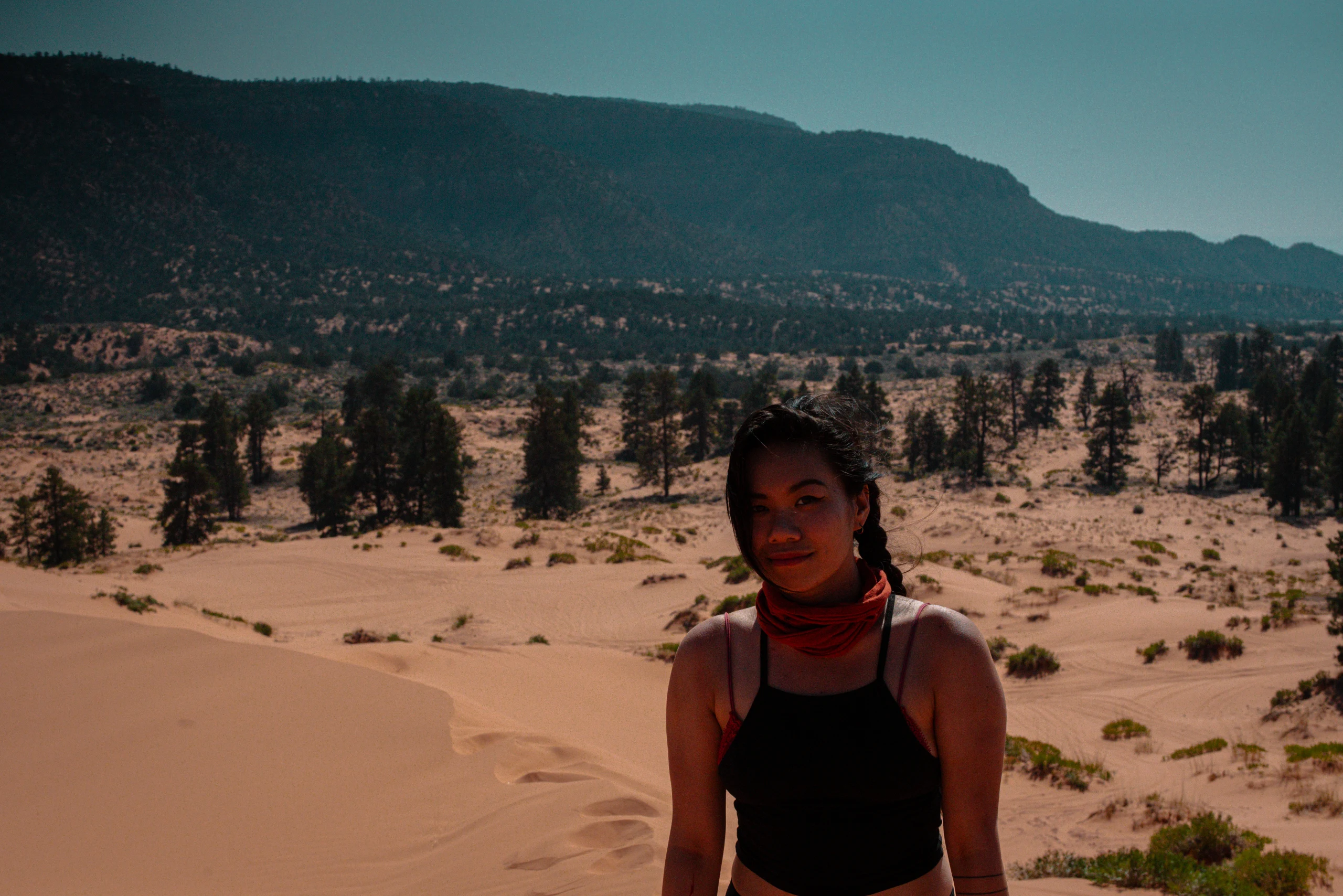 A person poses for a portrait in a softly lit field of pale desert dunes.