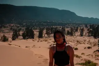 A person poses for a portrait in a softly lit field of pale desert dunes.