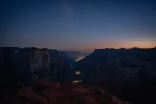 A starry night sky stretches above the dark outline of Zion's canyon walls.