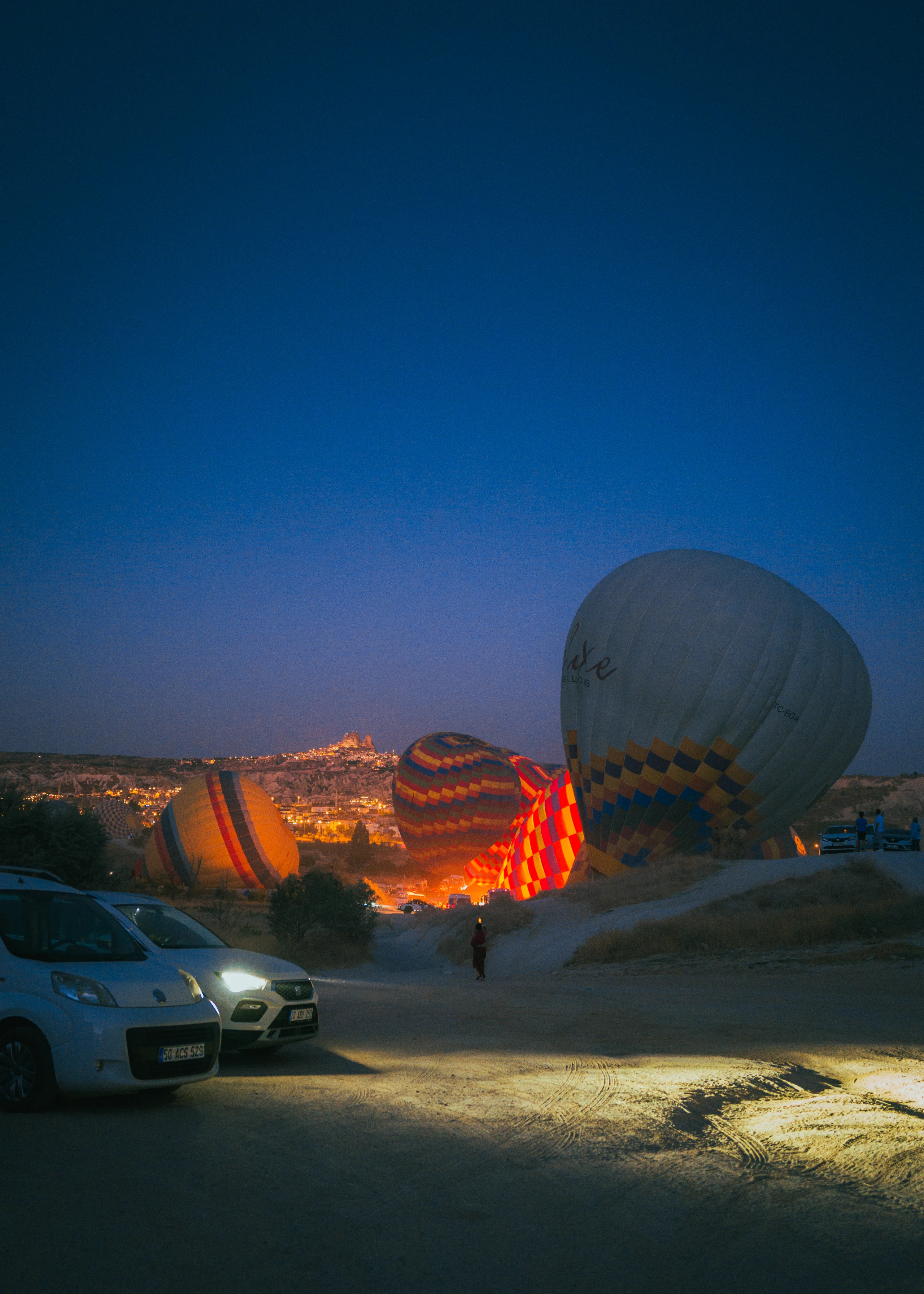 Vehicles and a large balloon on a field before dawn.