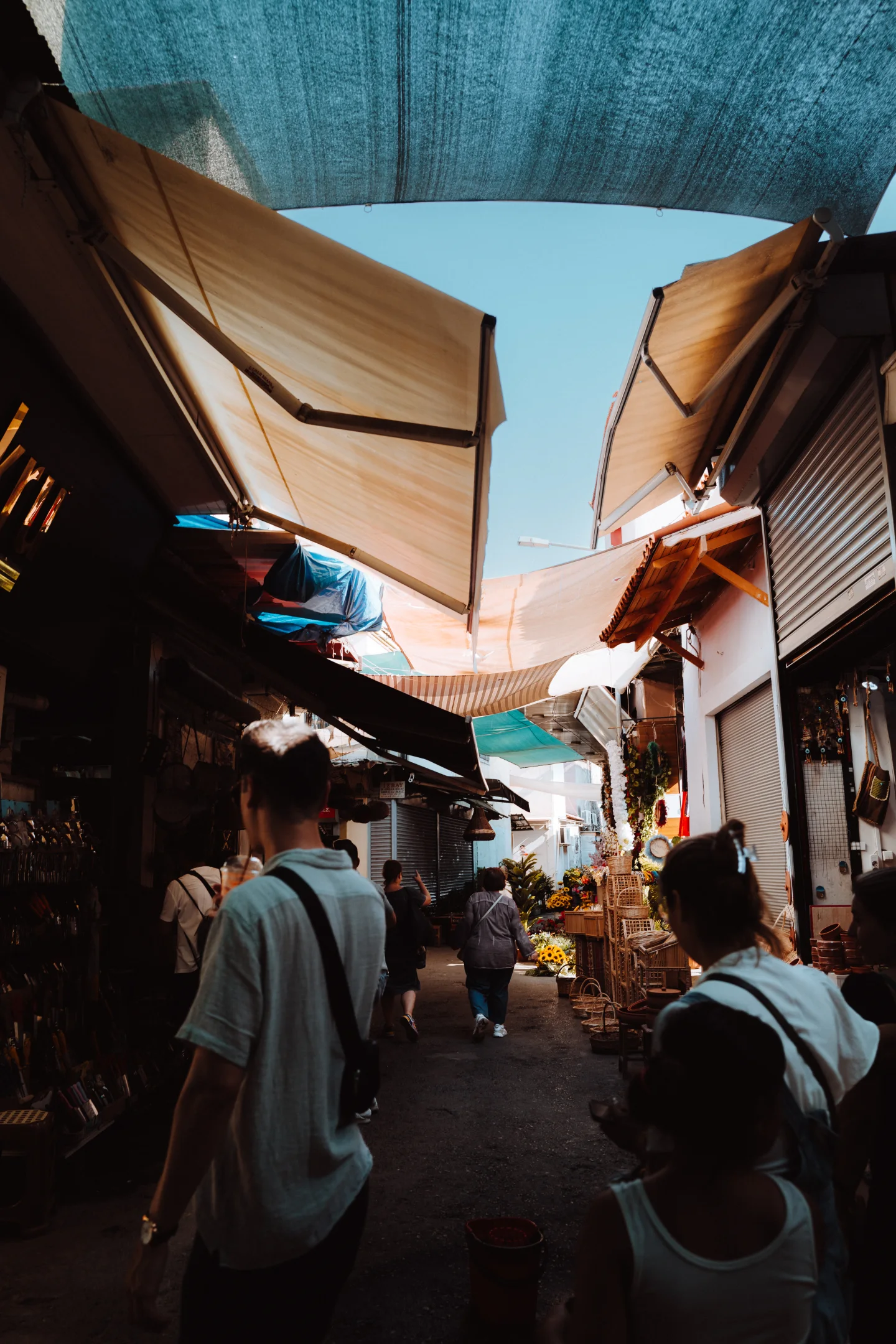 Narrow market alley beneath layered canopies.