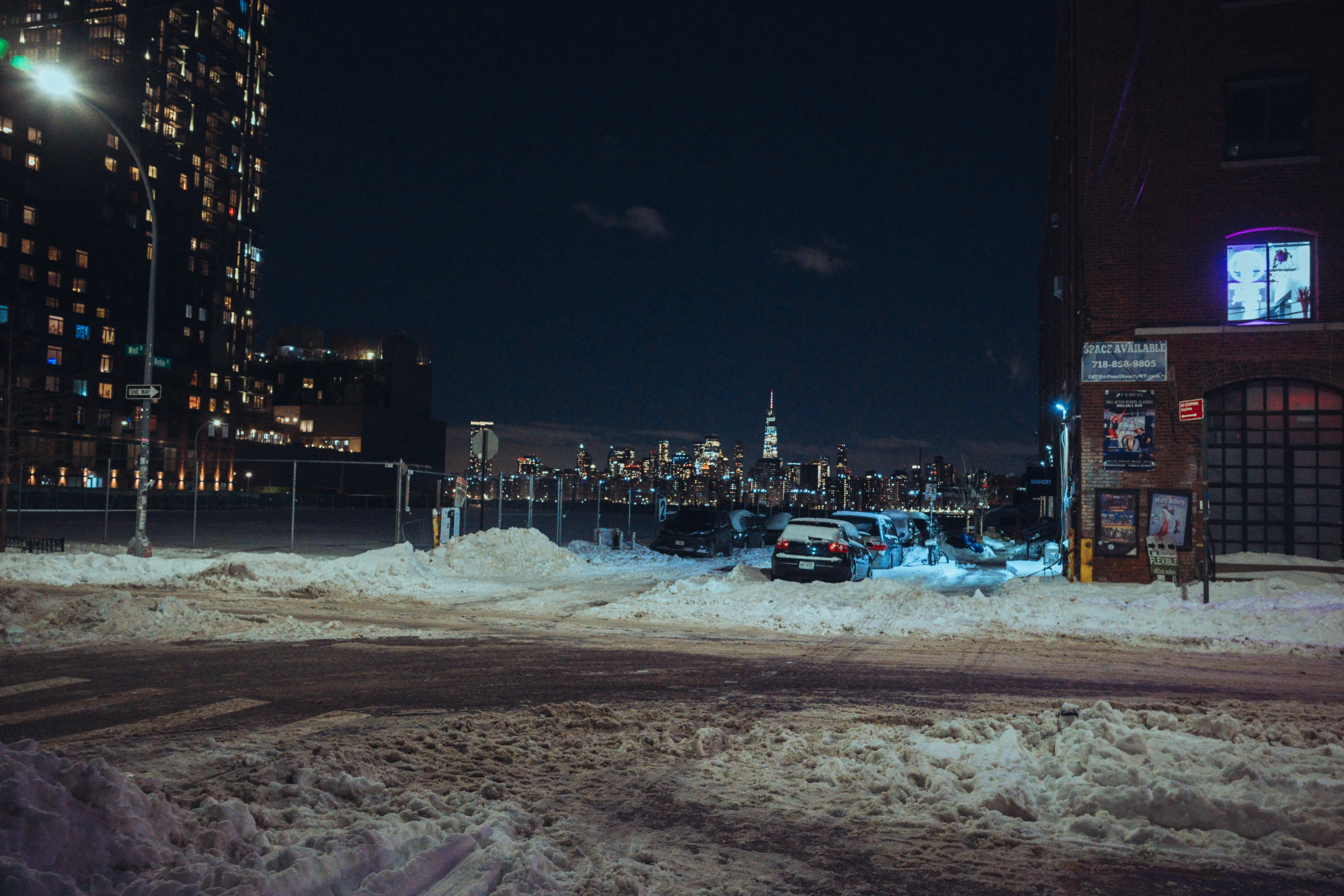 Snowy Brooklyn foreground with the illuminated Manhattan skyline across the river