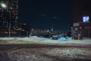 Snowy Brooklyn foreground with the illuminated Manhattan skyline across the river