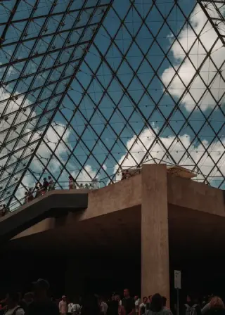 Geometric view of the Louvre pyramid against the sky.
