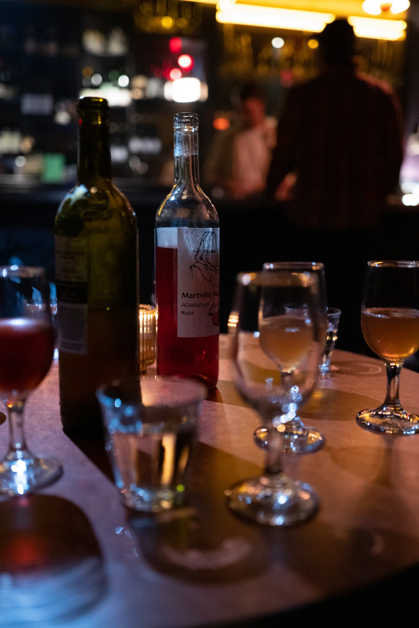 Wine and water glasses sit on a dimly lit table.