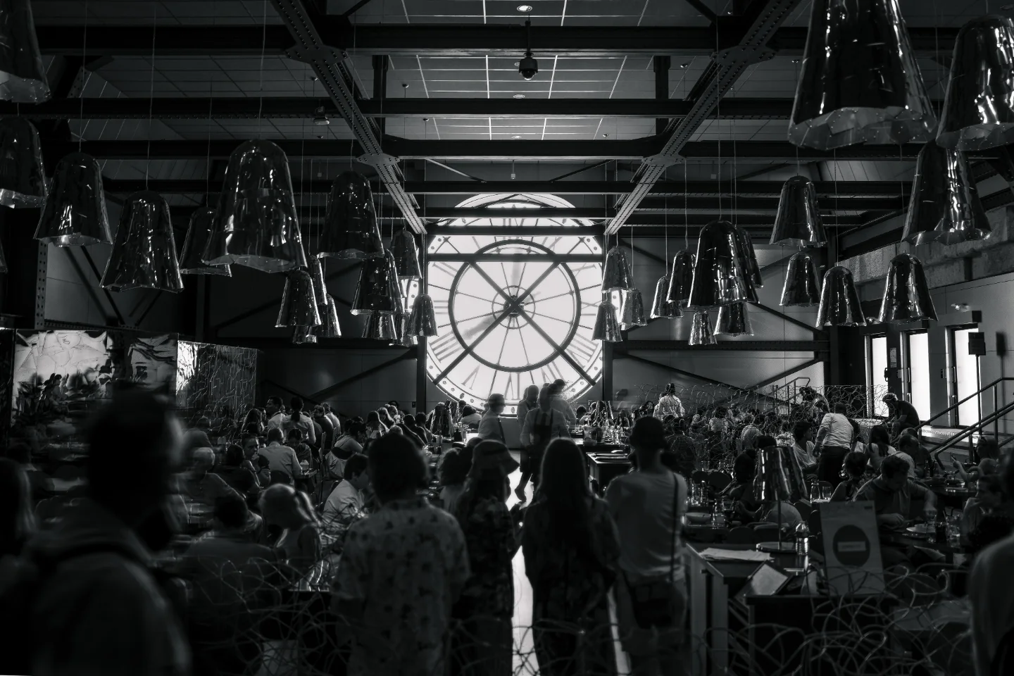 Crowded museum interior beneath the clock in black and white.