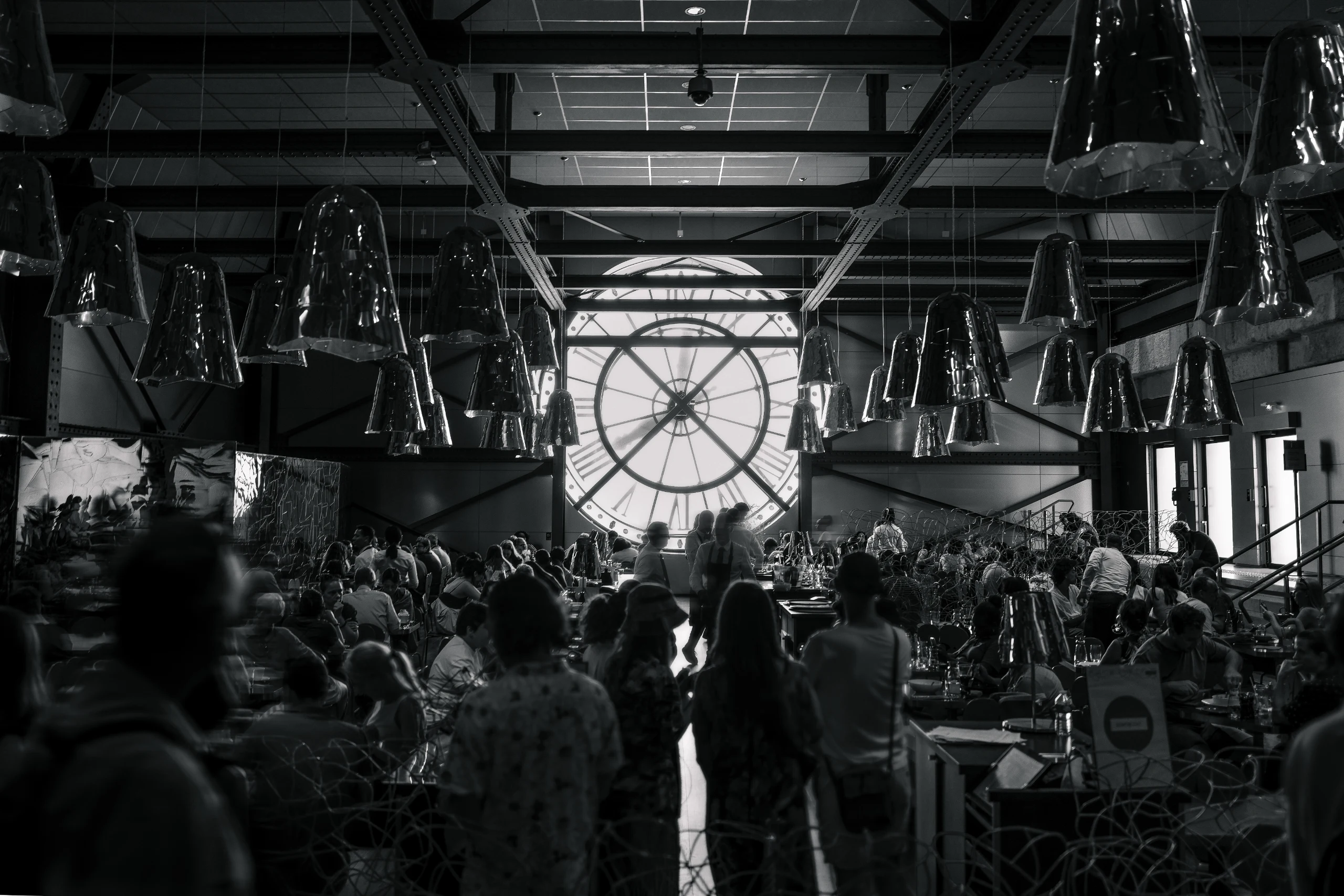 Crowded museum interior beneath the clock in black and white.